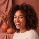 A happy young woman in her late 20s or early 30s smiles genuinely, conveying trust and satisfaction.